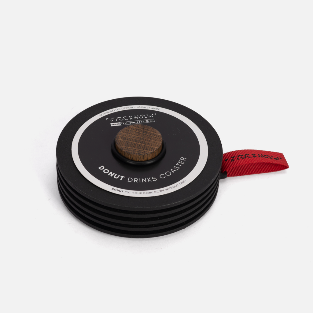 Stack of black drink coasters with a central donut-shaped coaster on a white background