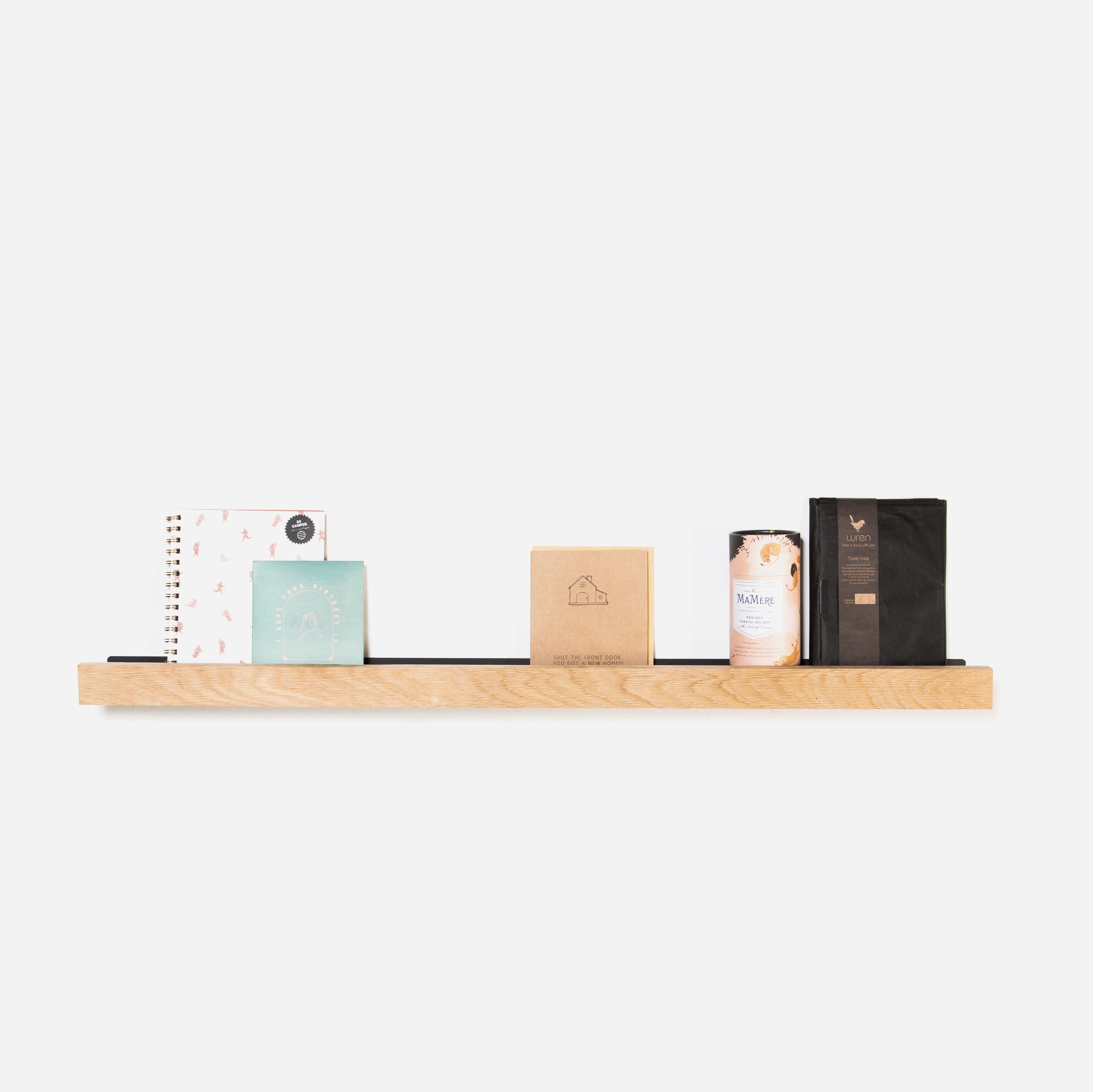 A natural oak lip shelf with various decorative items placed on it, against a white background.